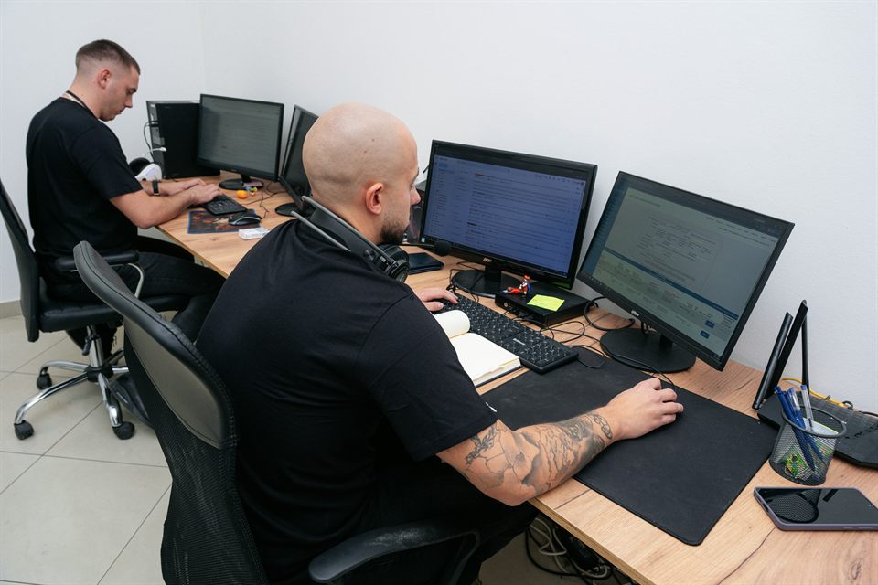 Colleagues working at neighboring desks with multiple monitors